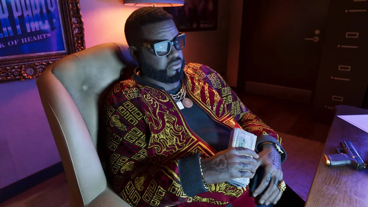 Boobie Ike in a patterned jacket, holding a stack of cash in a leather chair in his office
