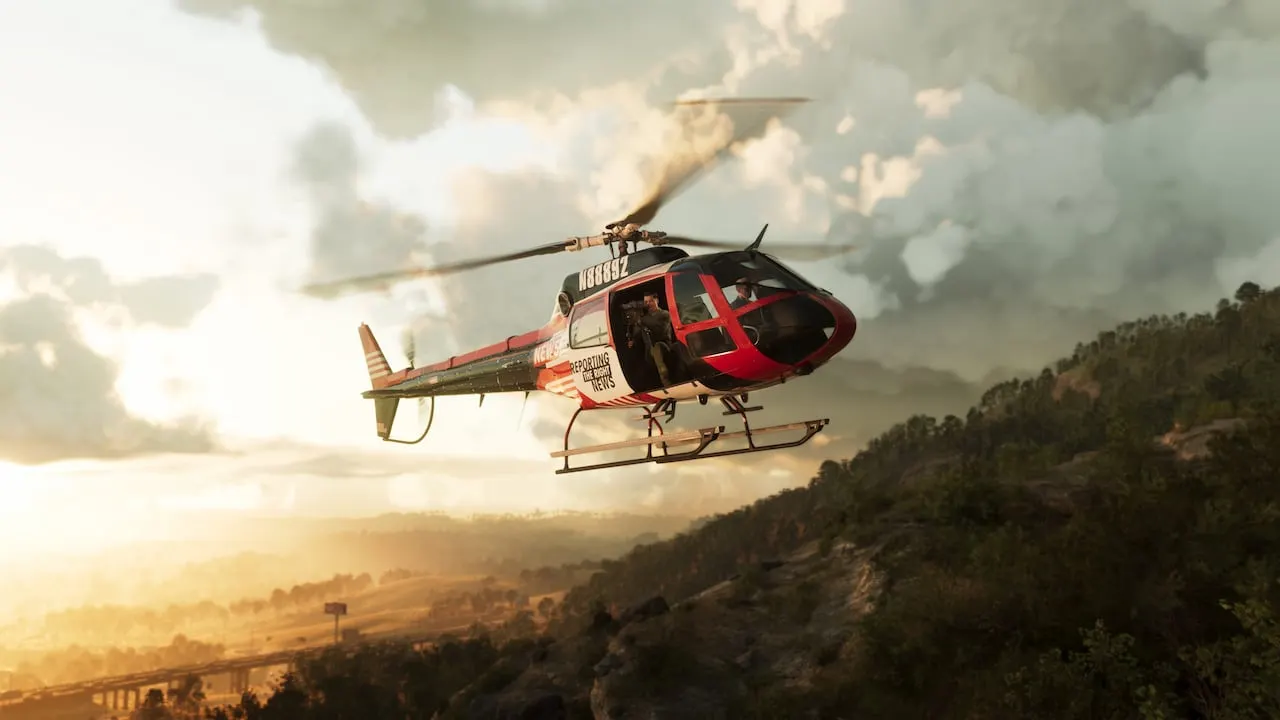 A red and white helicopter flying low over forested hills